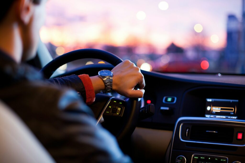 Fahrer mit Blick auf die Armbanduhr am Lenkrad in der Dämmerung — Sinnbild für die begrenzte Übergangsfrist beim Führerschein umschreiben in Deutschland